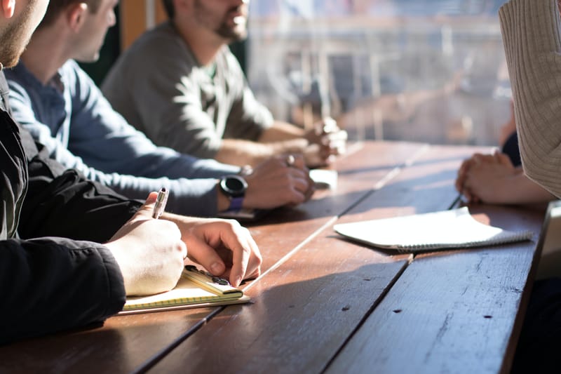 Men Working on Table with Notepads