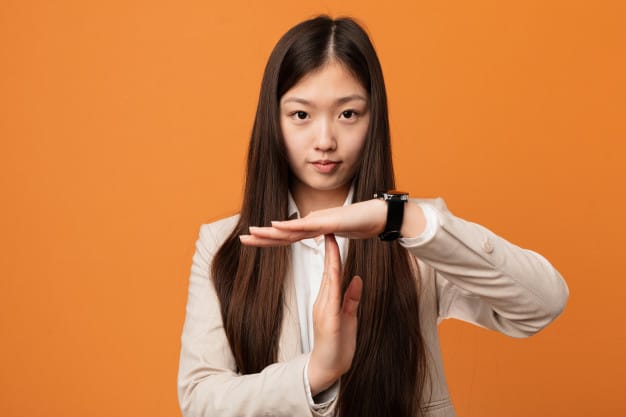 Young Chinese business woman showing timeout gesture